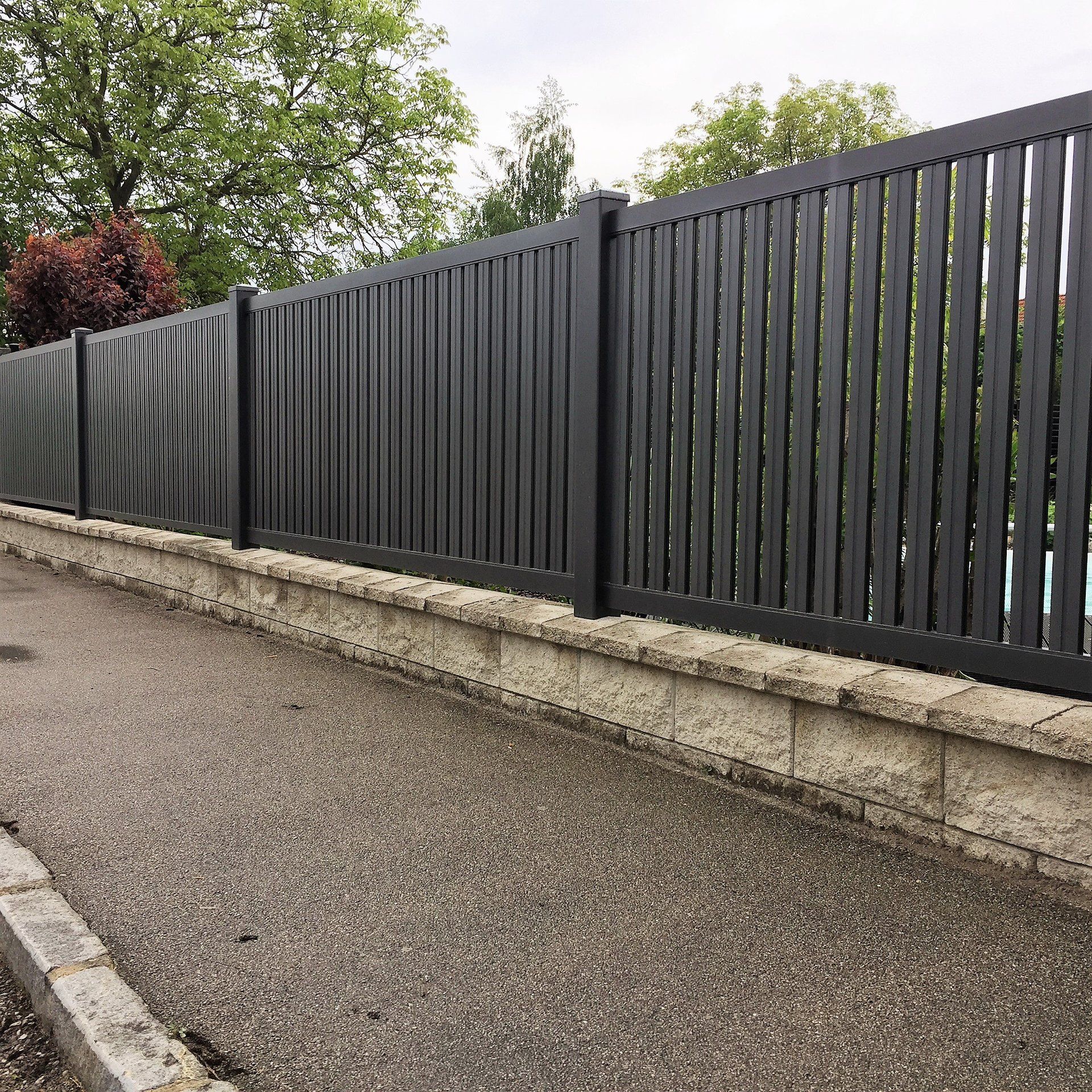 Am Straßenrand steht ein schwarzer Zaun.