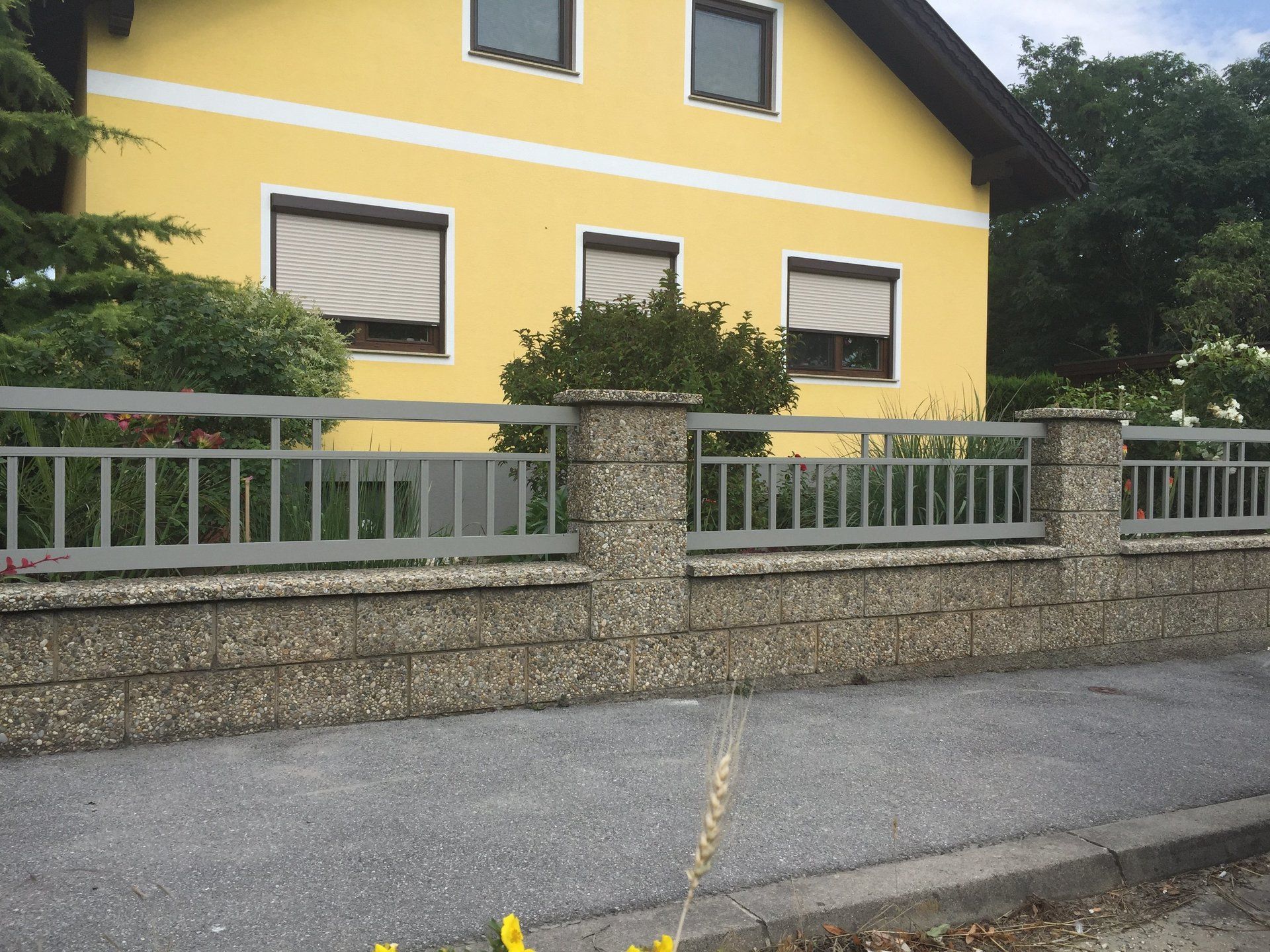 Ein gelbes Haus mit einem Zaun davor