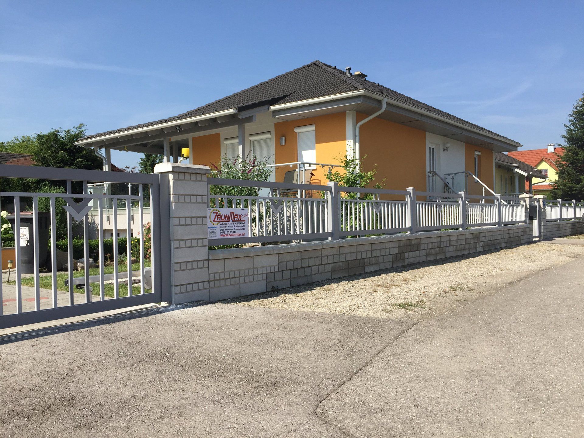 Ein Haus mit einem Zaun darum und einem Schild mit der Aufschrift 