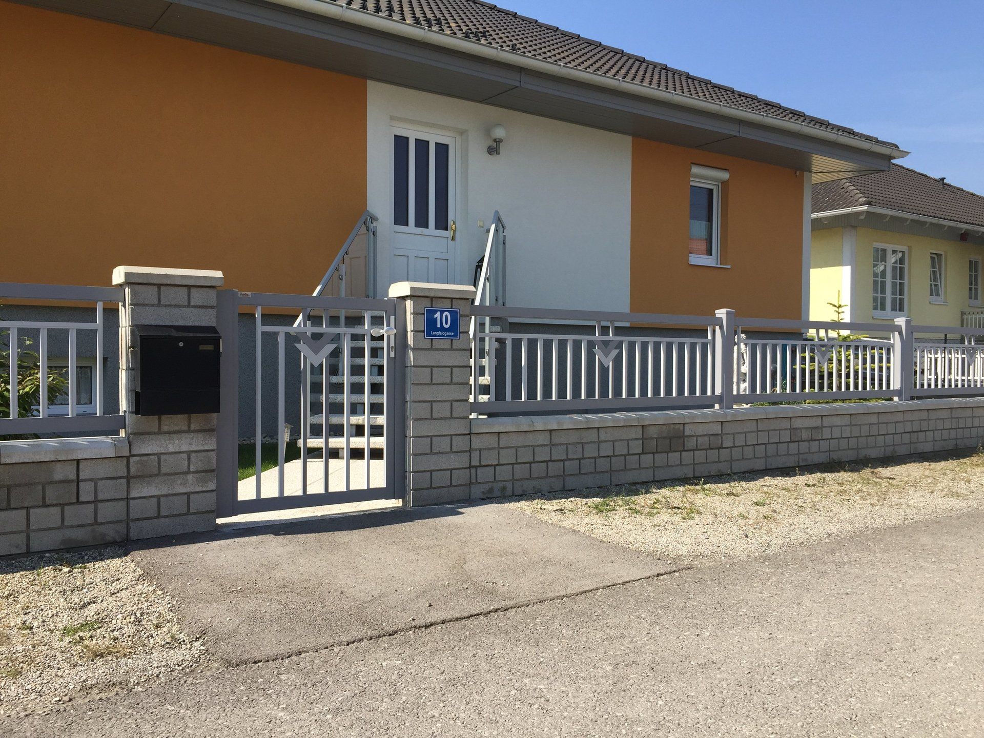 Ein Haus mit einem Zaun und einem Briefkasten davor