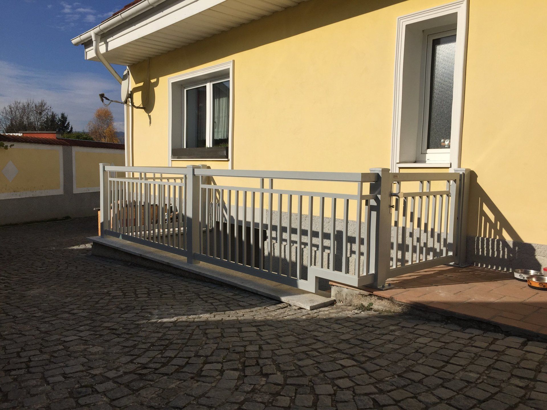 Ein gelbes Haus mit einem weißen Geländer davor.