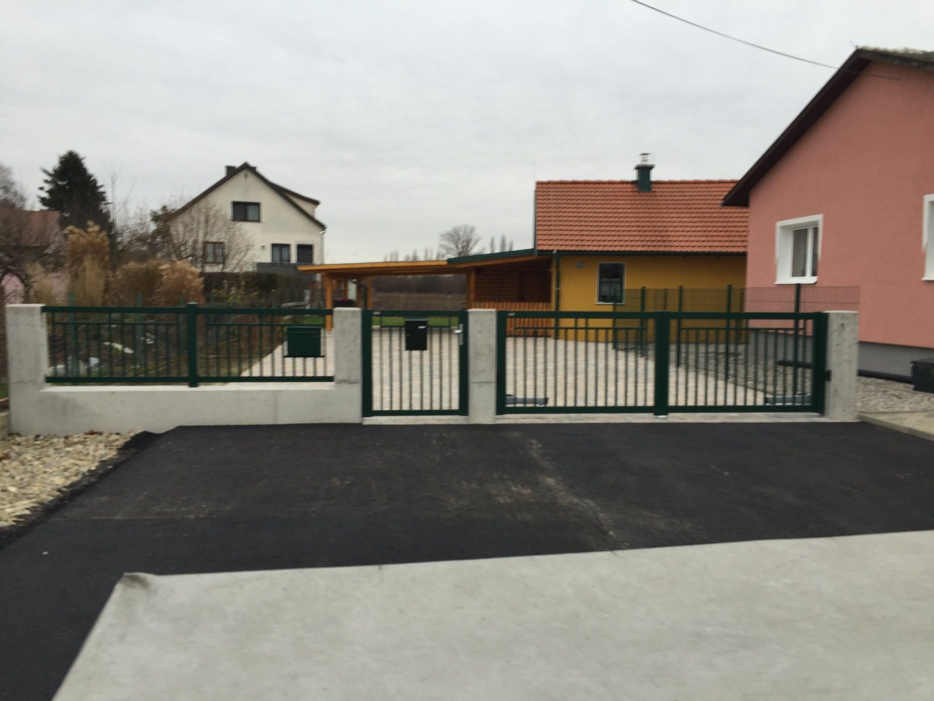 Eine Auffahrt mit einem Zaun und einem Haus im Hintergrund