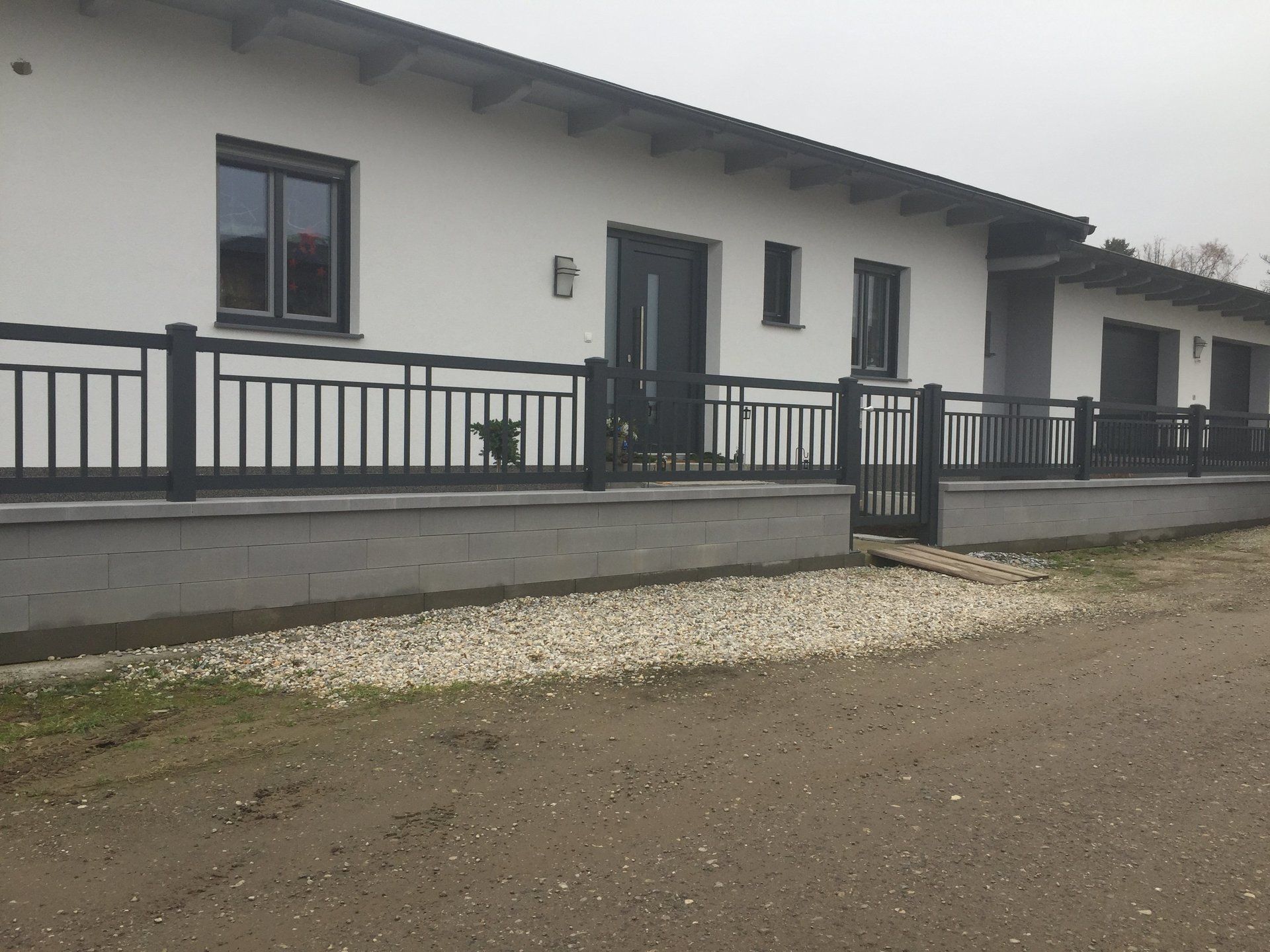 Ein weißes Haus mit einem schwarzen Zaun darum