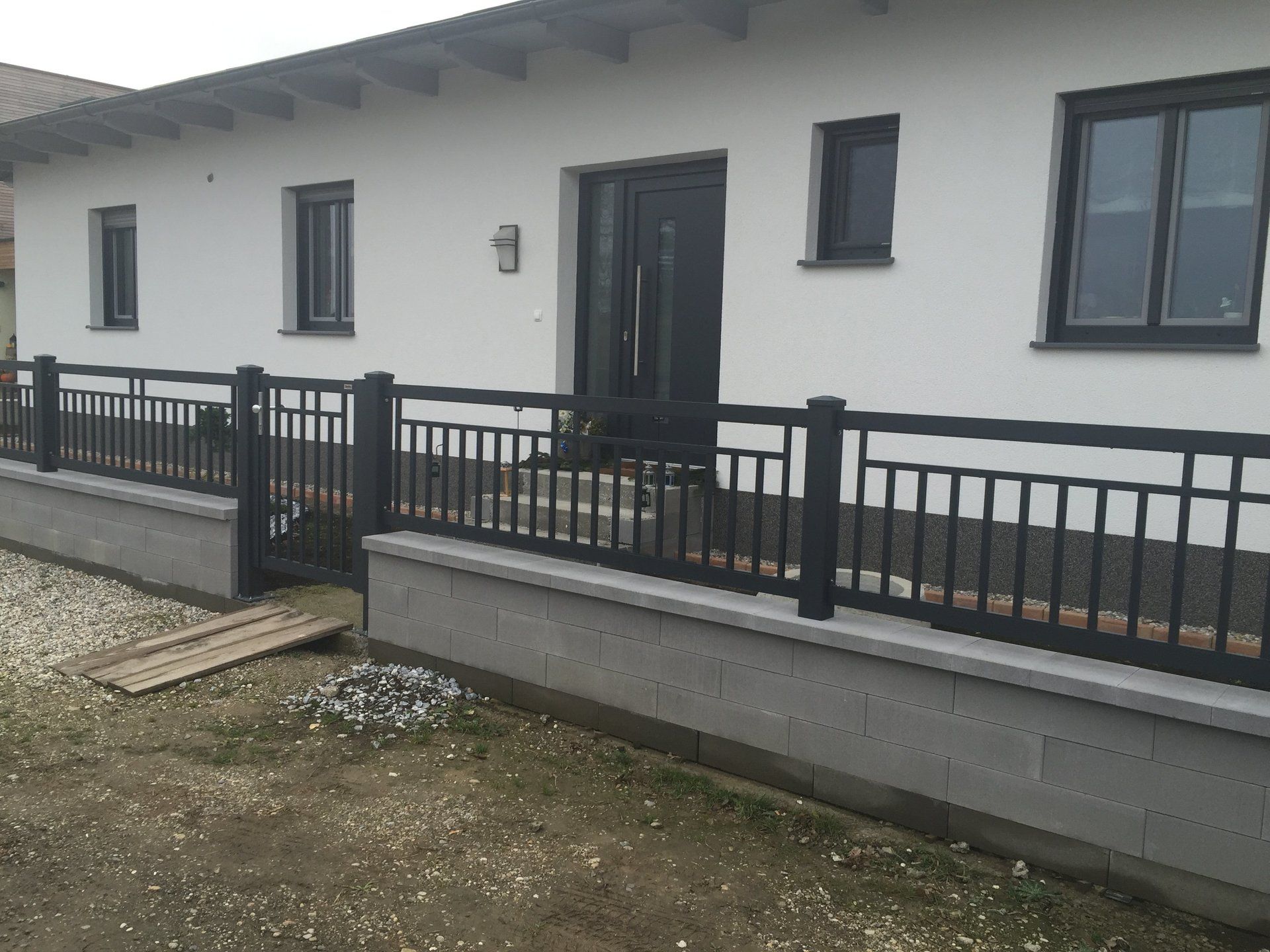 Ein weißes Haus mit einem schwarzen Zaun davor.