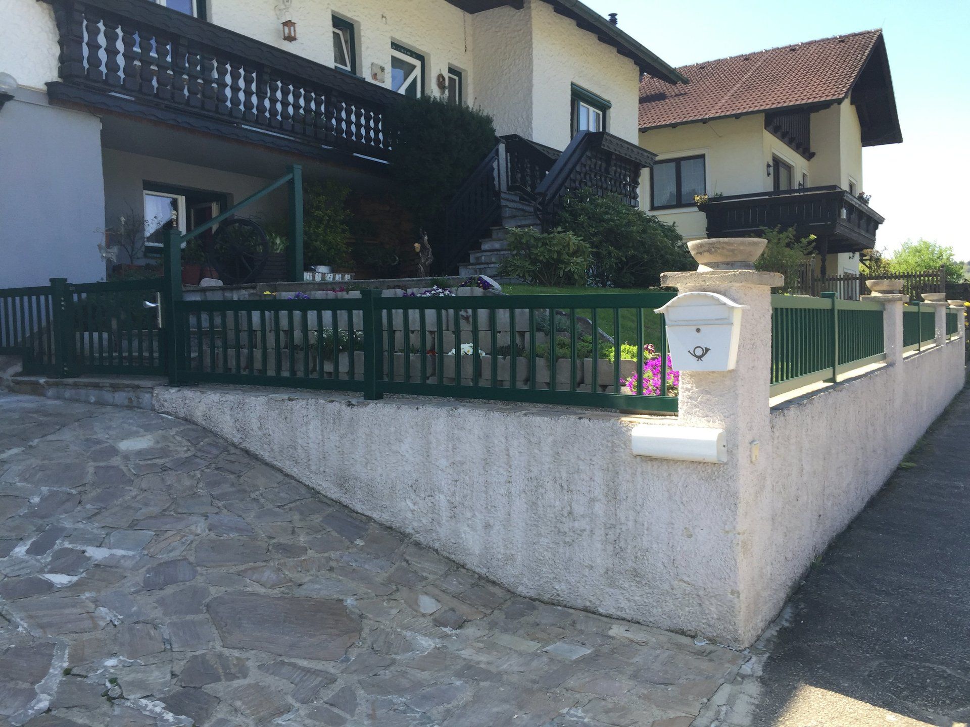 Ein Haus mit einem grünen Zaun und einem Briefkasten davor