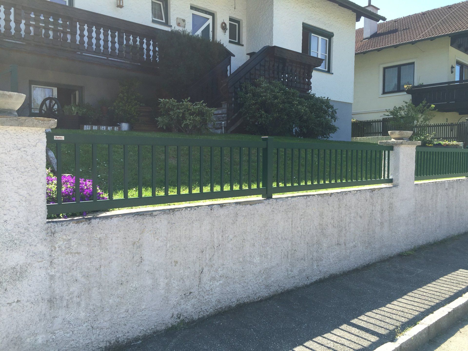 Ein weißes Haus mit einem grünen Zaun davor