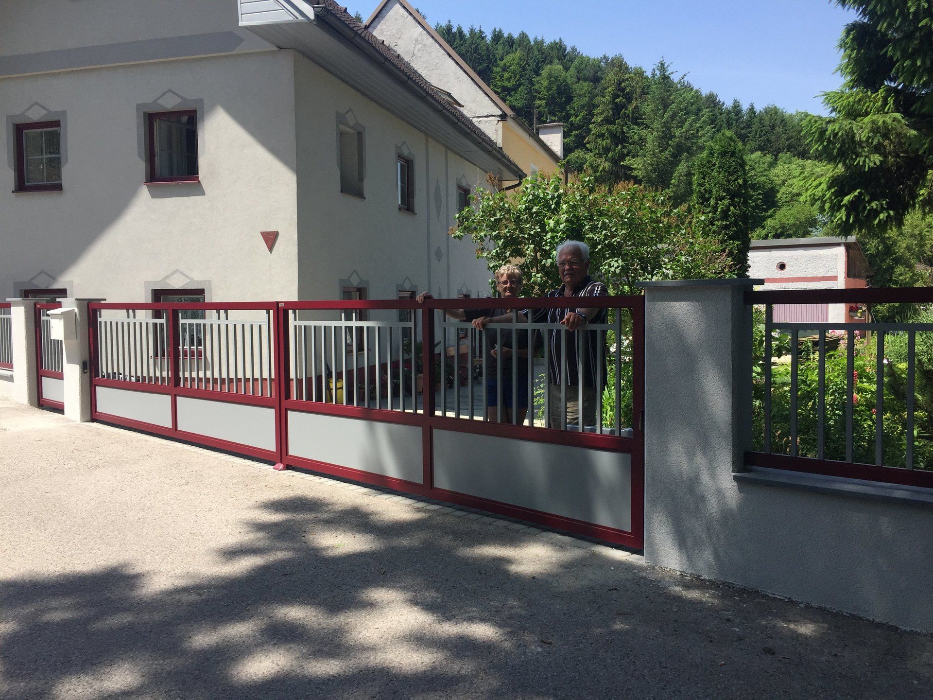 Ein Mann steht vor einem weißen Haus mit einem roten Zaun