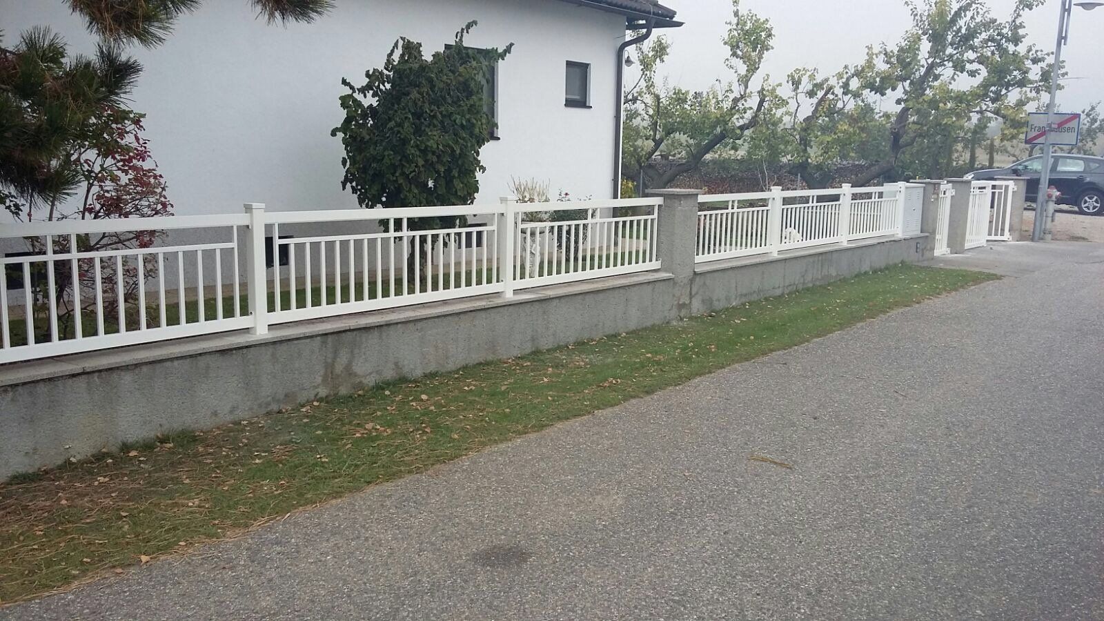 Ein weißer Zaun mit einem Haus im Hintergrund