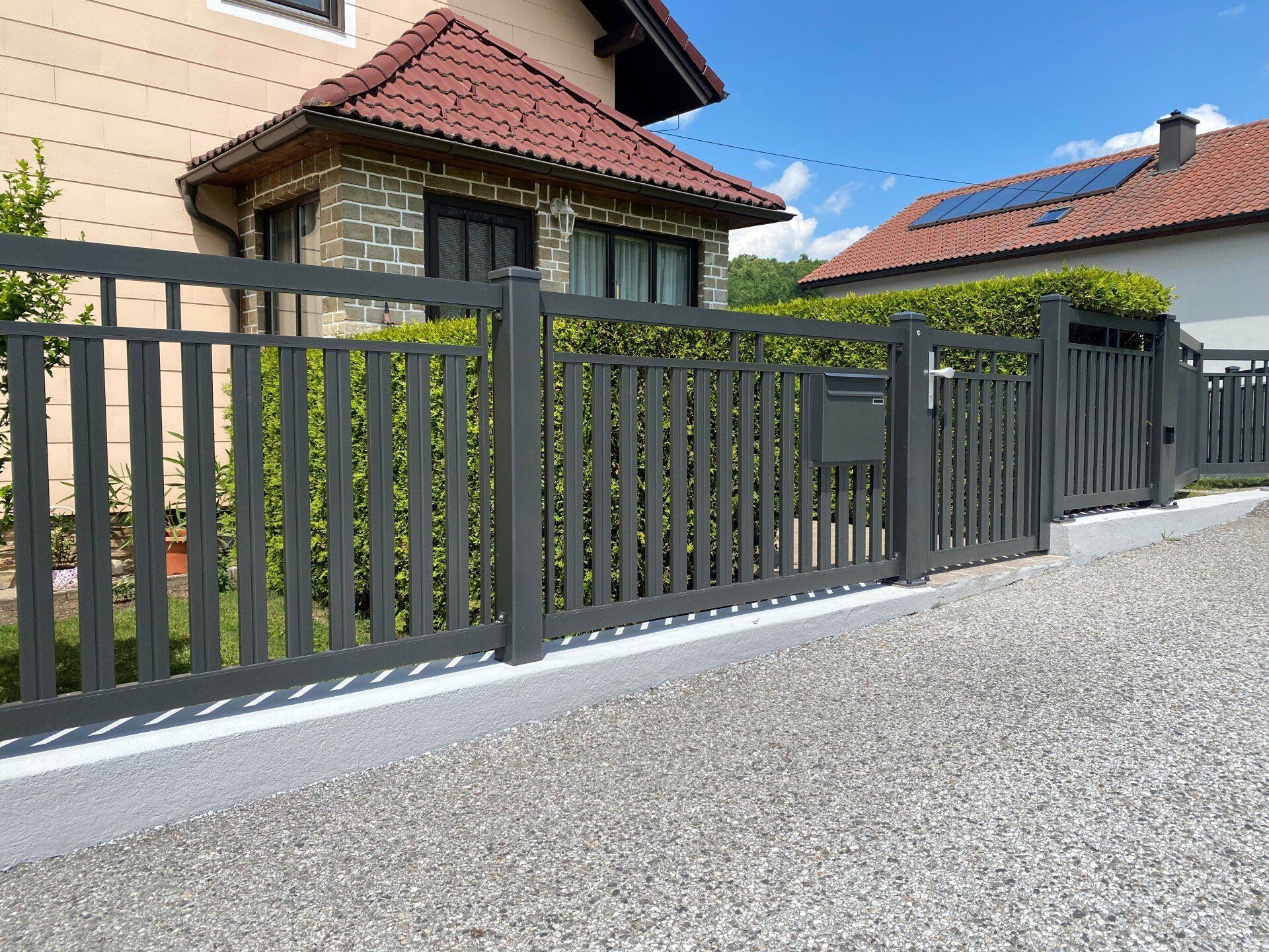 Ein Haus mit einem Zaun und einem Briefkasten davor.