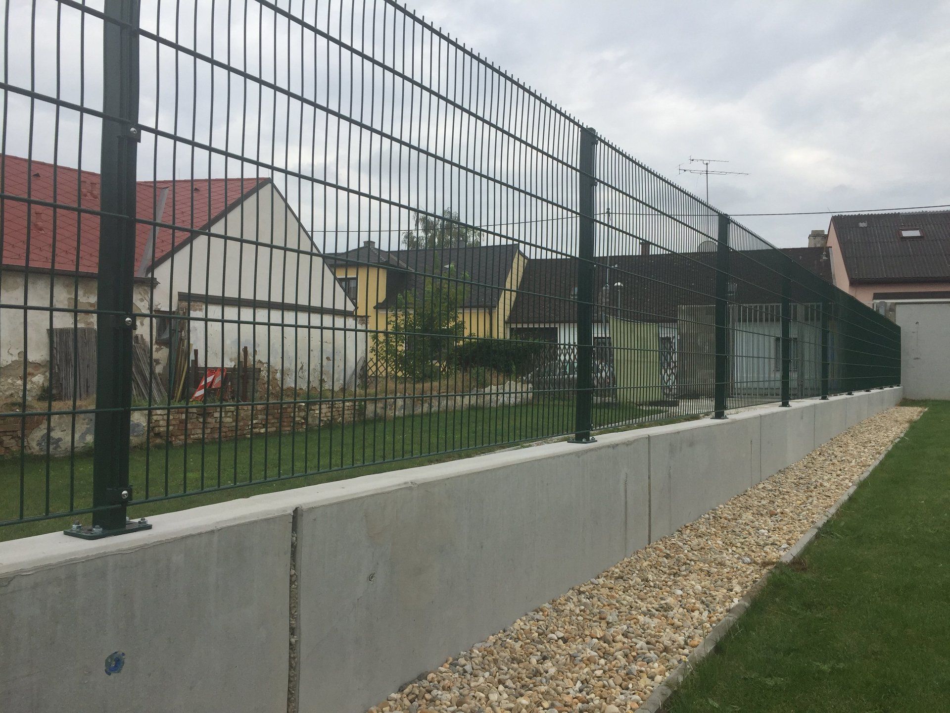 Ein schwarzer Zaun umgibt eine Betonmauer