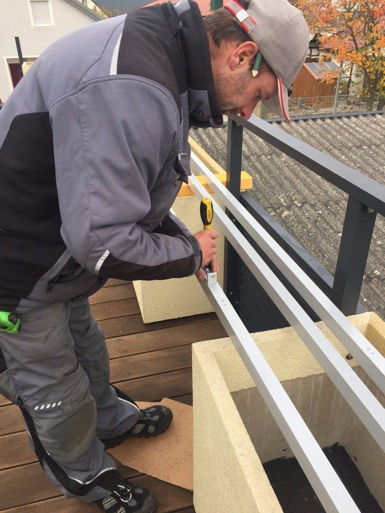 Ein Mann arbeitet an einem Balkongeländer.