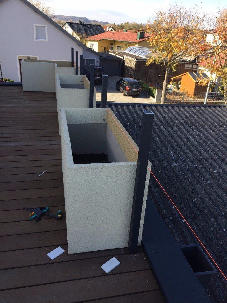 Eine Reihe von Pflanzgefäßen steht auf einem Holzdeck