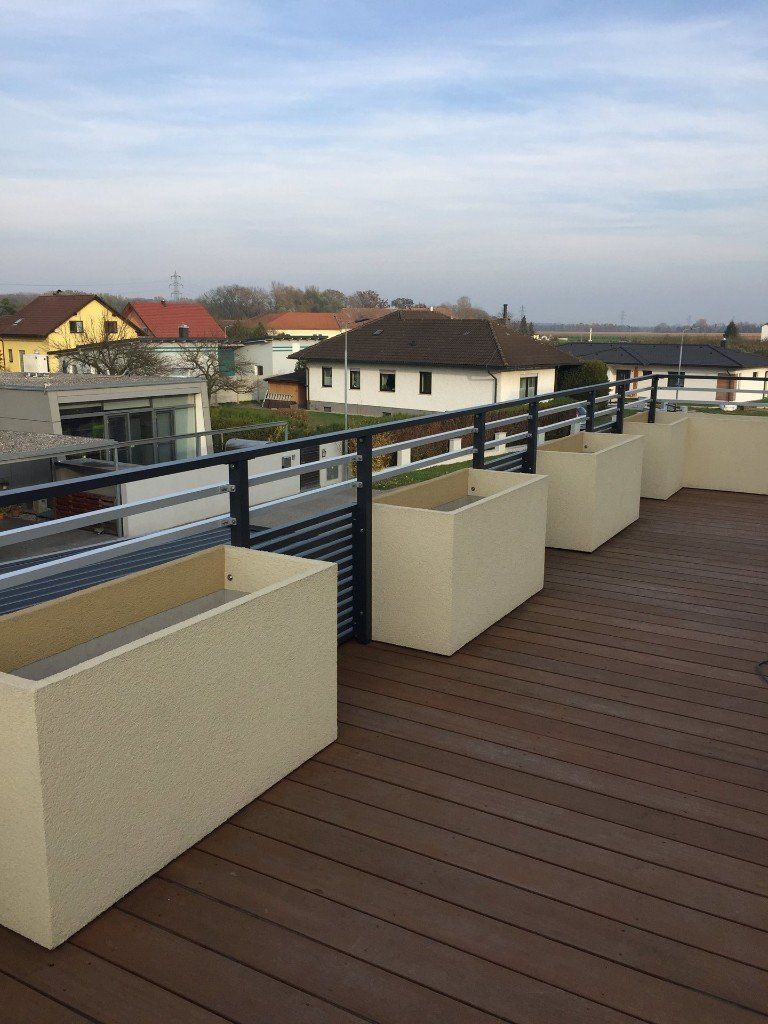 Ein Balkon mit Pflanzkübeln und Blick auf die Stadt