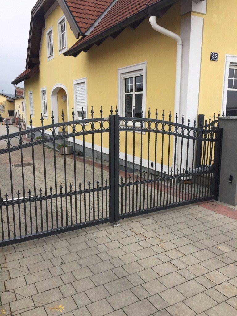 Ein gelbes Haus mit einem schwarzen Zaun davor