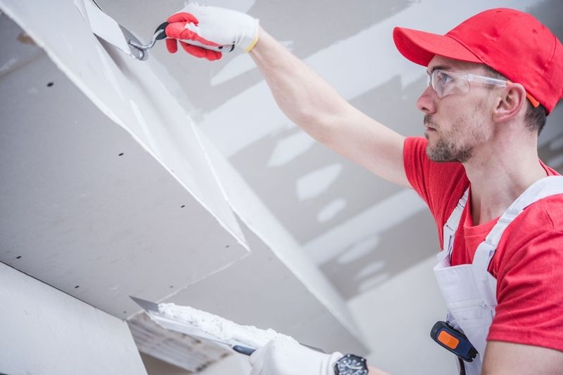 An drywall installation tradesman mudding drywall seams on a new installation project in Jersey City, New Jersey. 