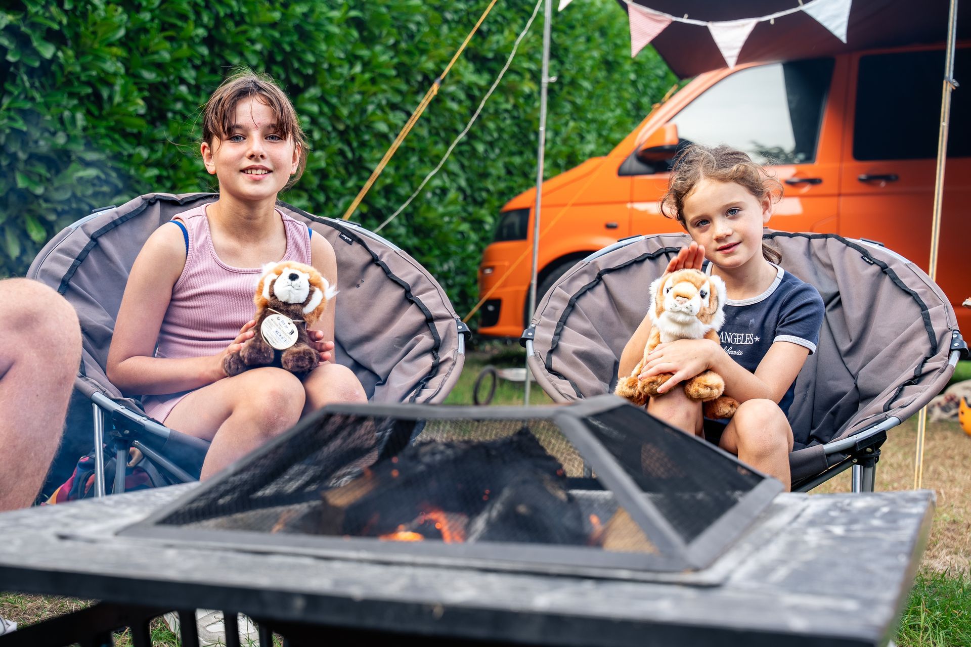 Campground with RVs and cyclists under a cloudy blue sky.