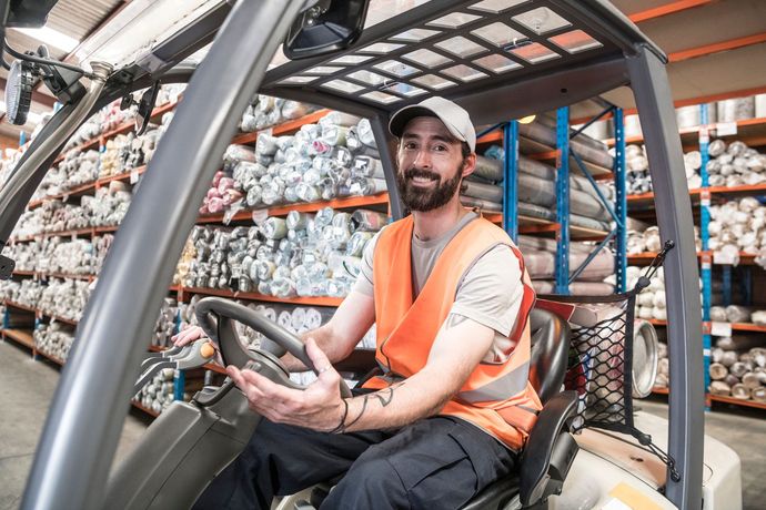 A man is driving a forklift in a warehouse.