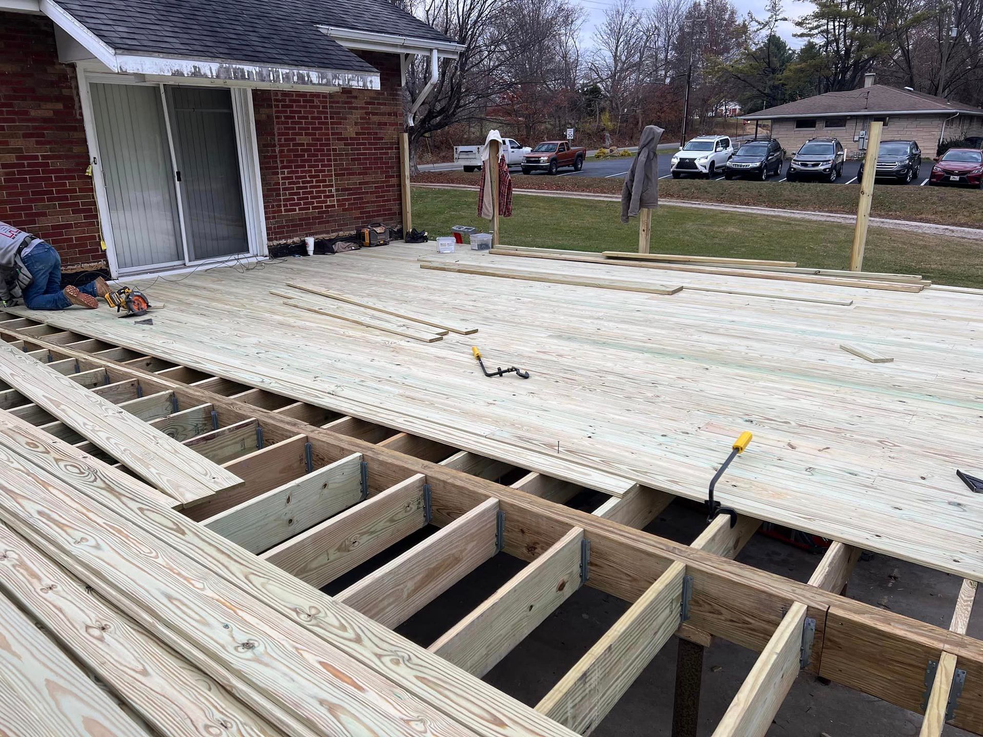 A Man Is Working On A Wooden Deck In Front Of A Brick House - Princeton, IN - J. Koberstein Construction