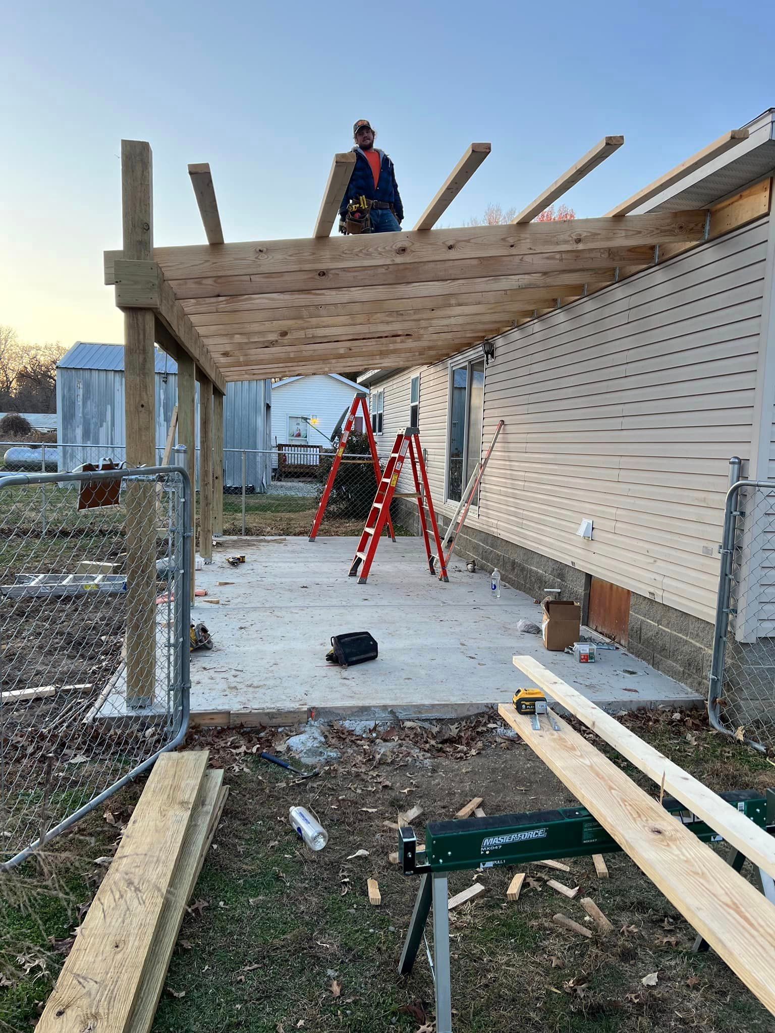 A Man Is Standing On Top Of A Wooden Structure In Front Of A House - Princeton, IN - J. Koberstein Construction