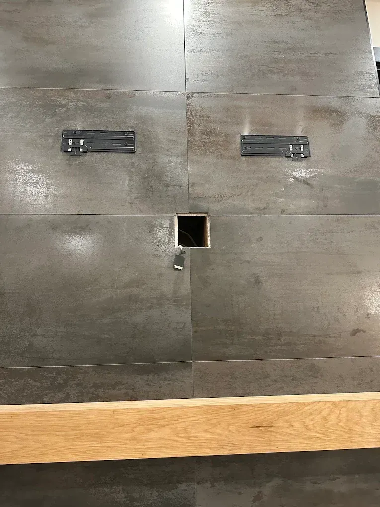 Gray metal tiled surface with two metal brackets and a central square opening. A wooden beam rests below.