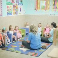 Teacher leading a circle time with toddlers in a colorful preschool classroom