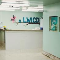 Empty reception area with white desk, mint walls, and LWICD logo on the back wall