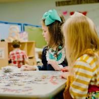 Children seated at a table, drawing and coloring in a classroom setting
