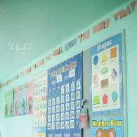 Classroom wall with colorful educational posters and alphabet letters displayed above the board