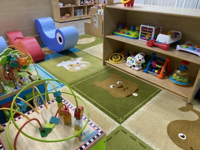 Colorful preschool playroom with toys, shelves, and green animal-shaped rugs