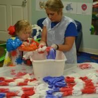 Two people dyeing white fabric red and blue in a classroom craft activity