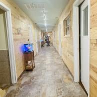 Long hallway with wood-paneled walls, tiled floor, and a small glowing aquarium on a stand