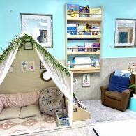 Cozy pastel living room with a small indoor tent, wall shelves, and a brown chair by a blue wall