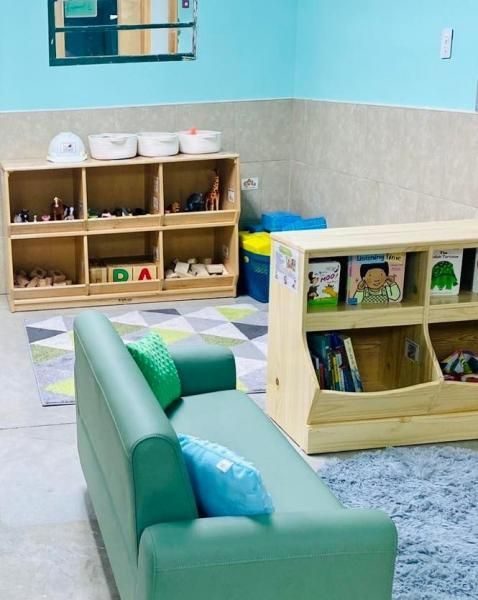 Children’s playroom with green sofa, low wooden shelves, and toys on a checkered floor