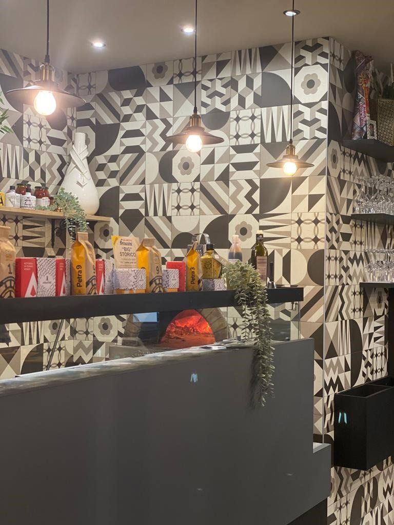 Un ristorante con una parete decorata con motivi geometrici e uno scaffale con delle bottiglie sopra.