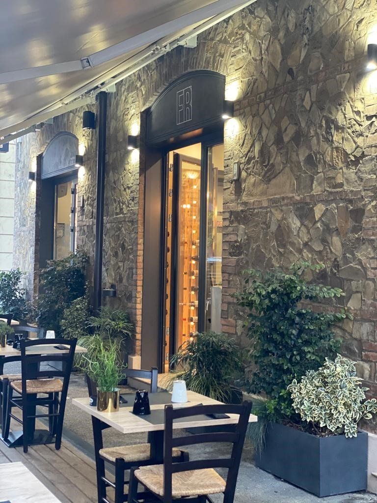 Un ristorante con tavoli e sedie di fronte a un muro di pietra.