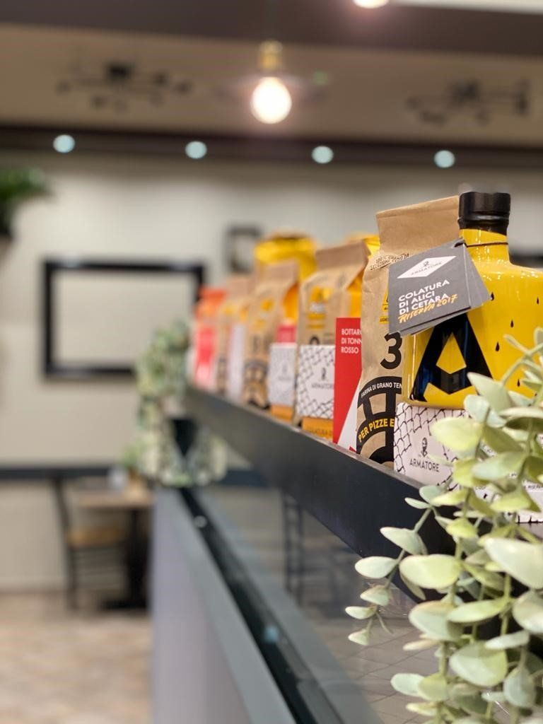 Uno scaffale pieno di bottiglie e sacchetti di cibo in un ristorante.