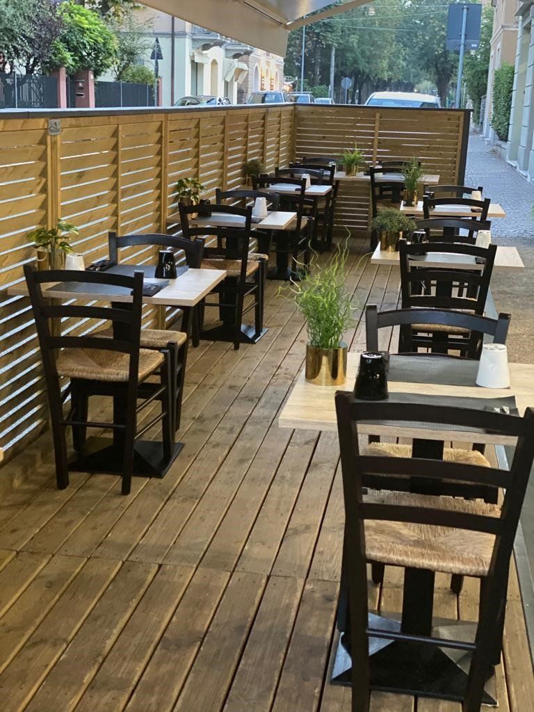 Una terrazza in legno con tavoli e sedie.