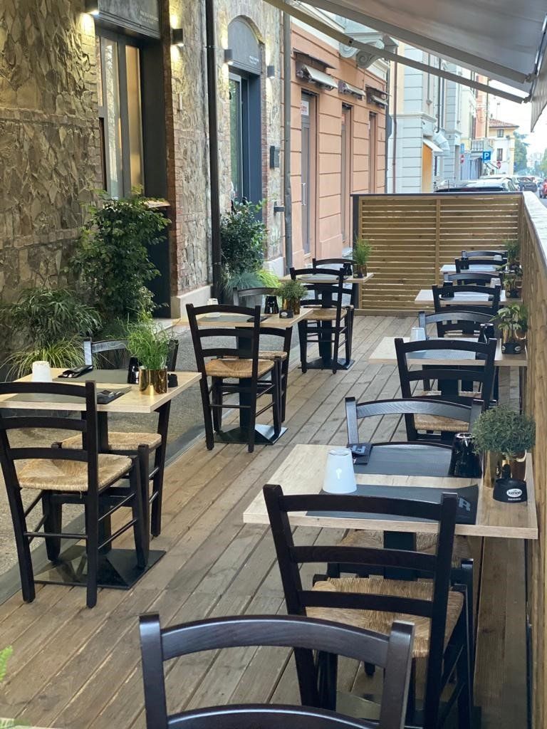 Un ristorante con tavoli e sedie su una terrazza di legno.