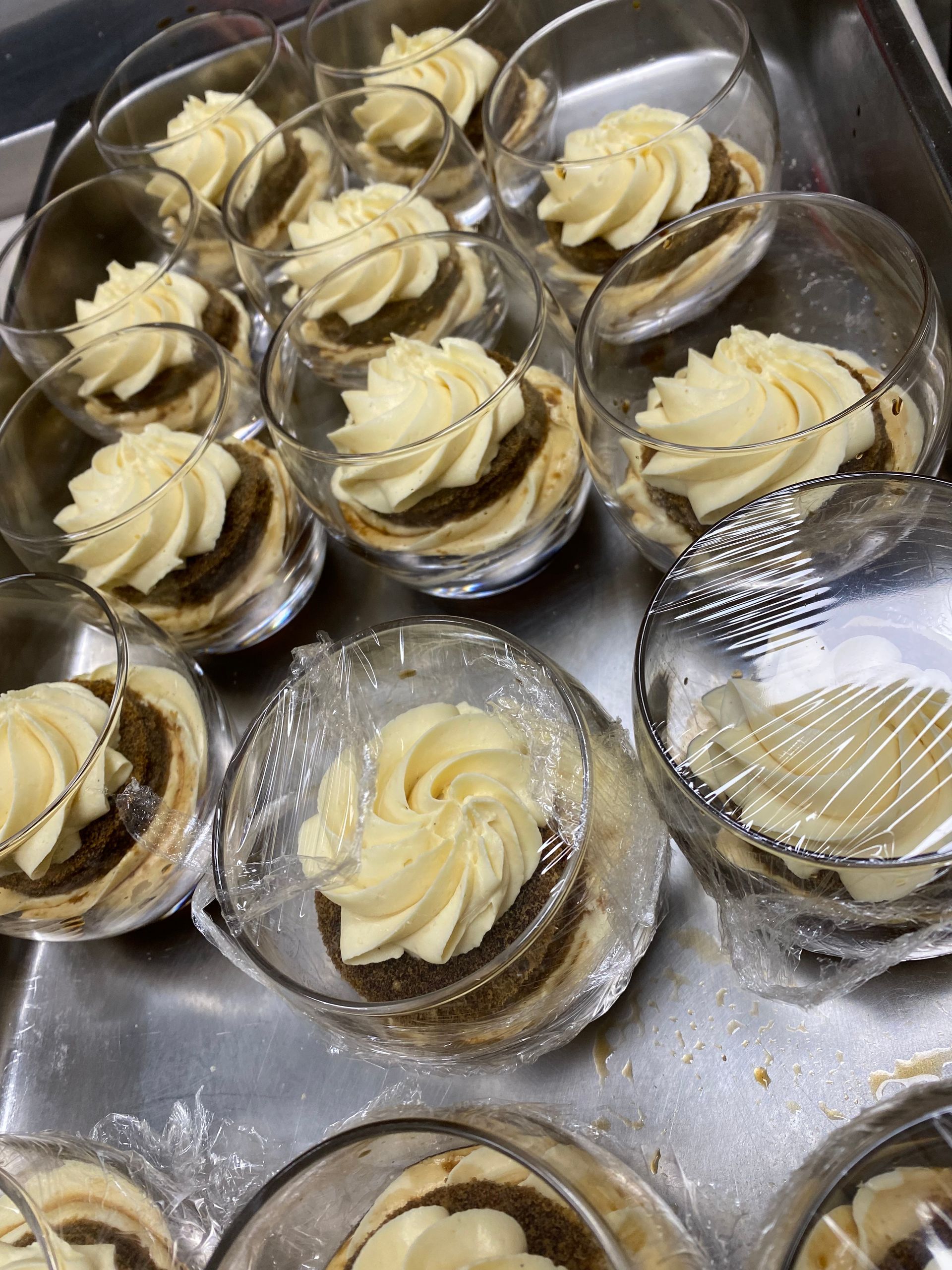 Un vassoio di dolci in bicchieri con panna montata sopra.