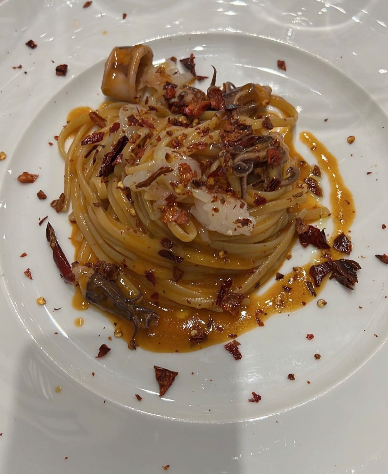 Un piatto bianco condito con spaghetti e salsa