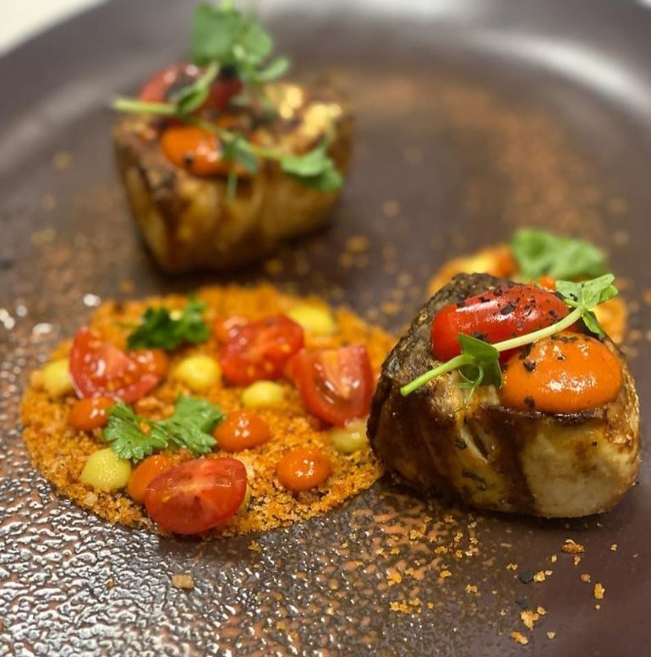 Un primo piano di un piatto di cibo con sopra dei pomodori