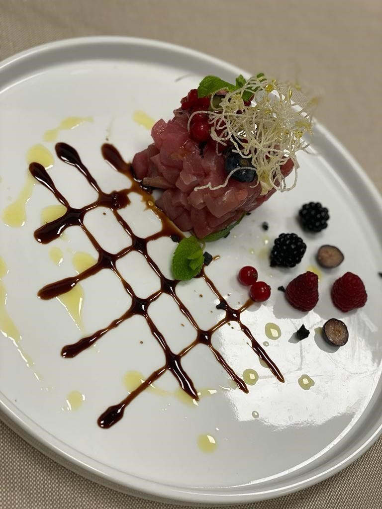 Un piatto bianco sormontato da un pezzo di carne e bacche