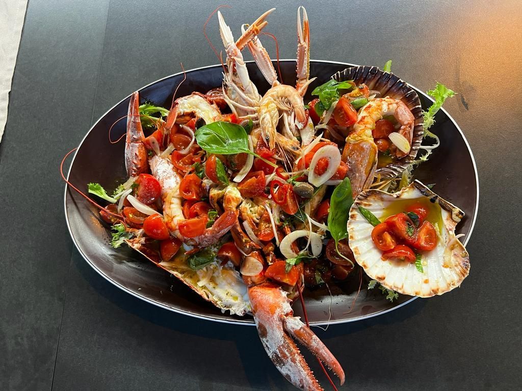 Un piatto di cibo con gamberi e capesante su un tavolo.