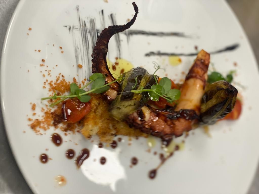 Un primo piano di un piatto di cibo con un polpo sopra.