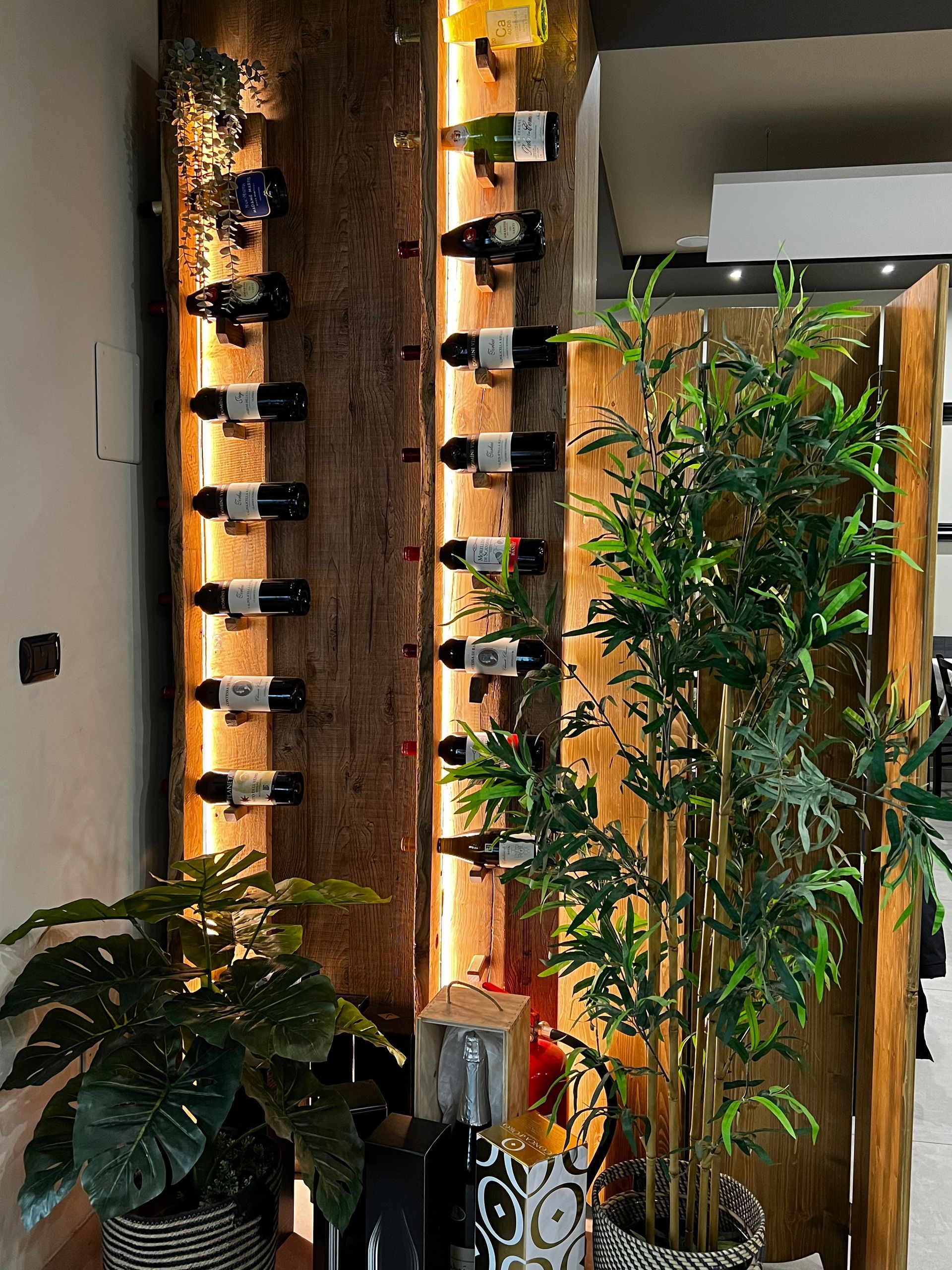 Un portabottiglie in legno pieno di bottiglie di vino e piante.