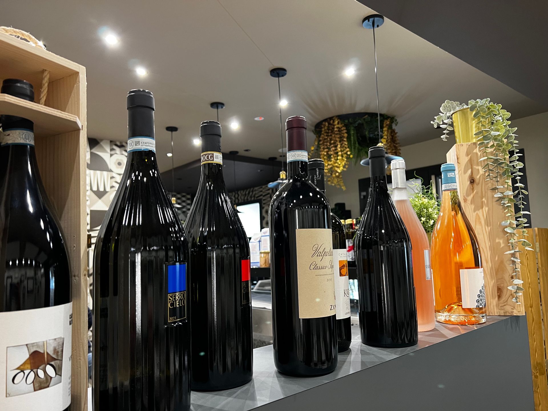 Una fila di bottiglie di vino appoggiate su un bancone.