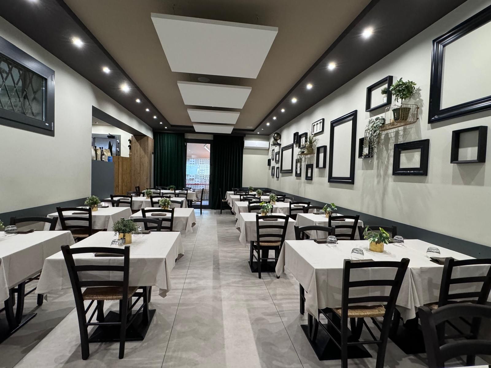 Una lunga sala da pranzo con tavoli e sedie in un ristorante