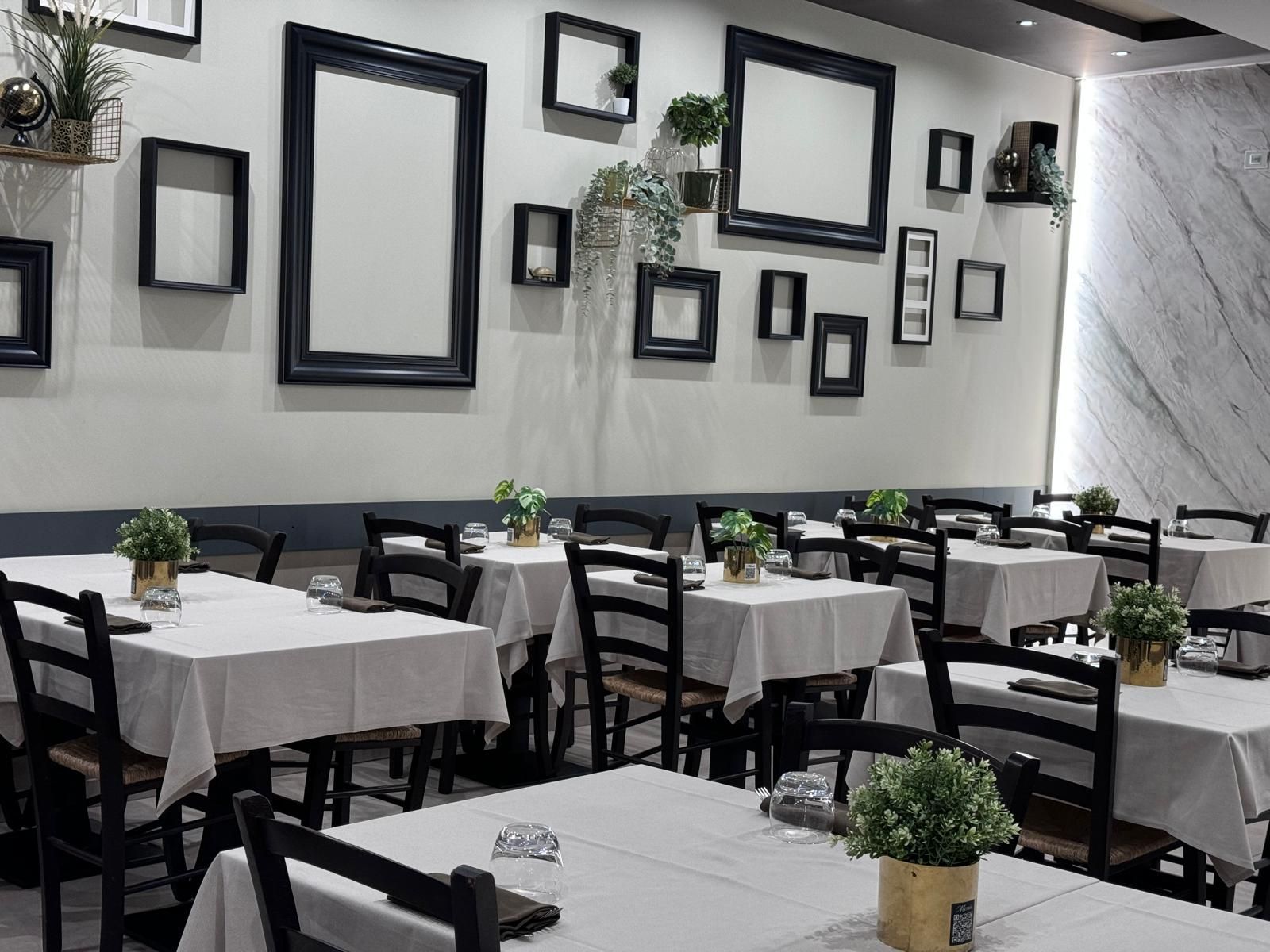 Un ristorante con tavoli e sedie e cornici sul muro