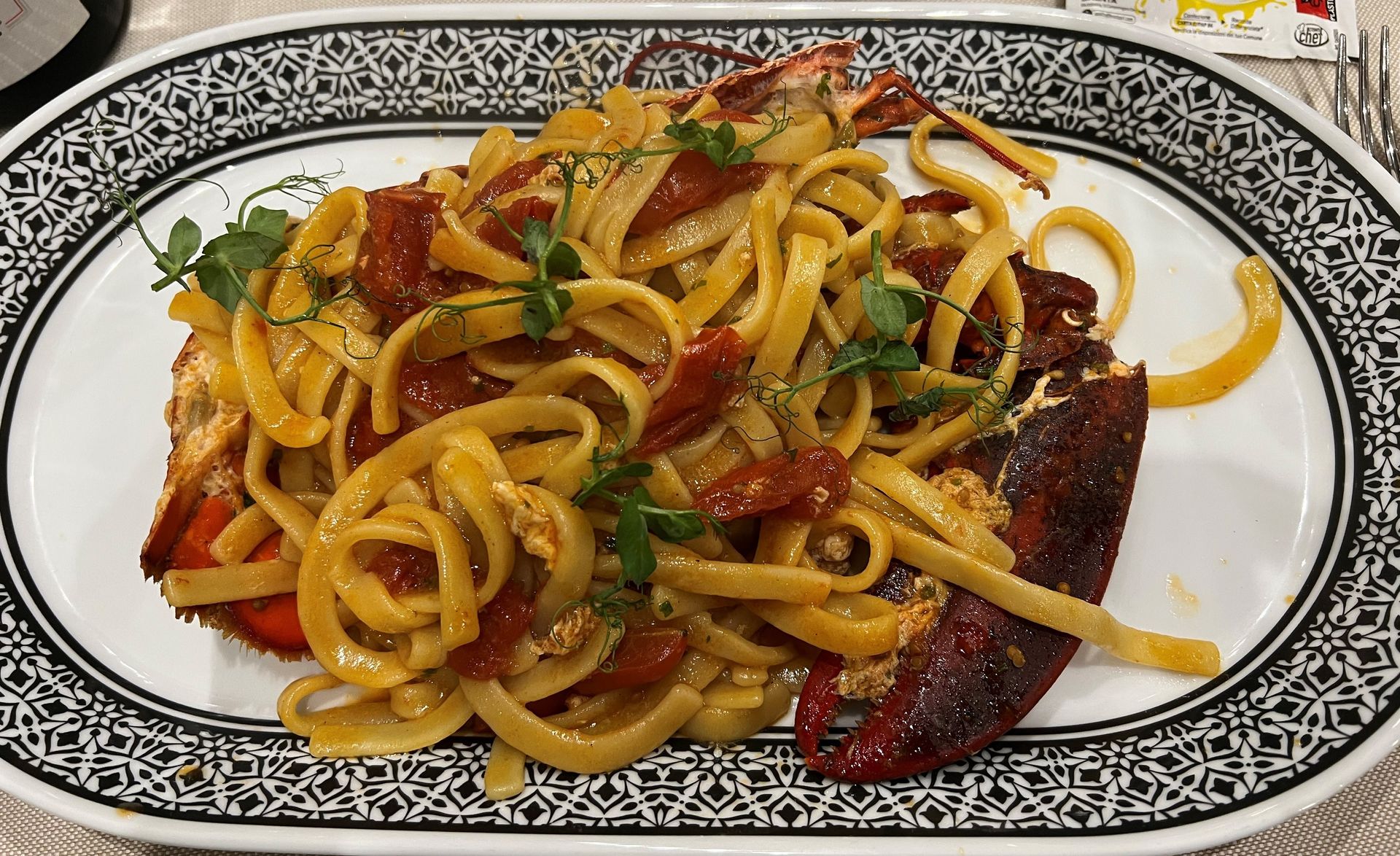 Un piatto bianco con sopra tagliatelle e carne su un tavolo.