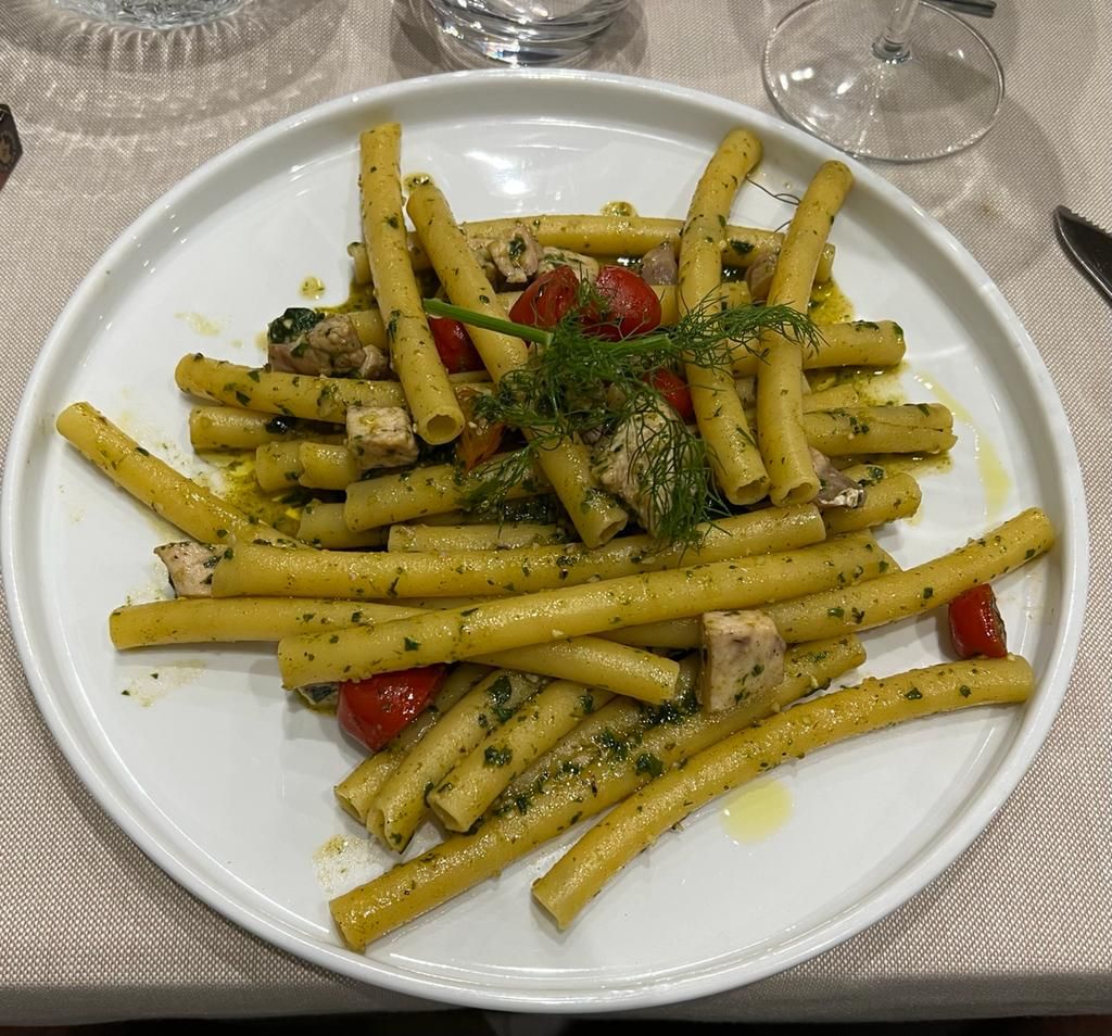Un piatto bianco con sopra pasta e pomodori su un tavolo